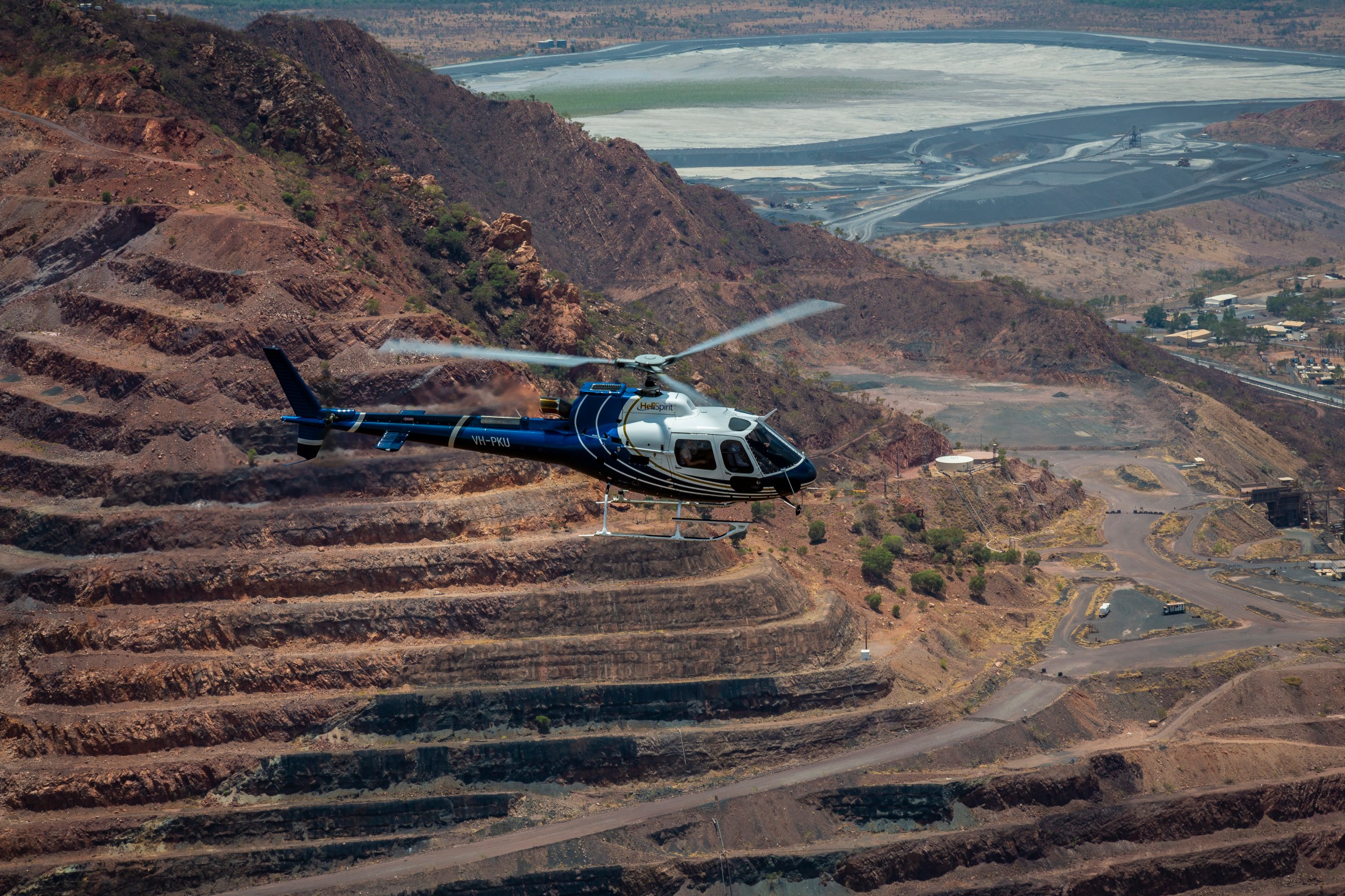 Helicopter flying over terraced landscape near a large body of water.