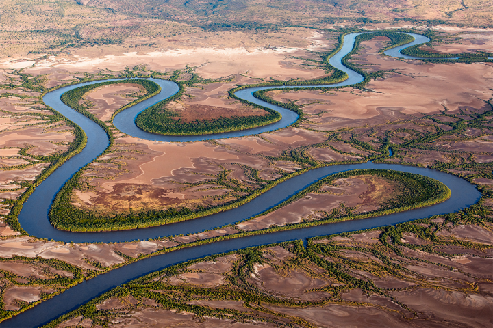 Aerial view of a winding river flowing through a dry, barren landscape.