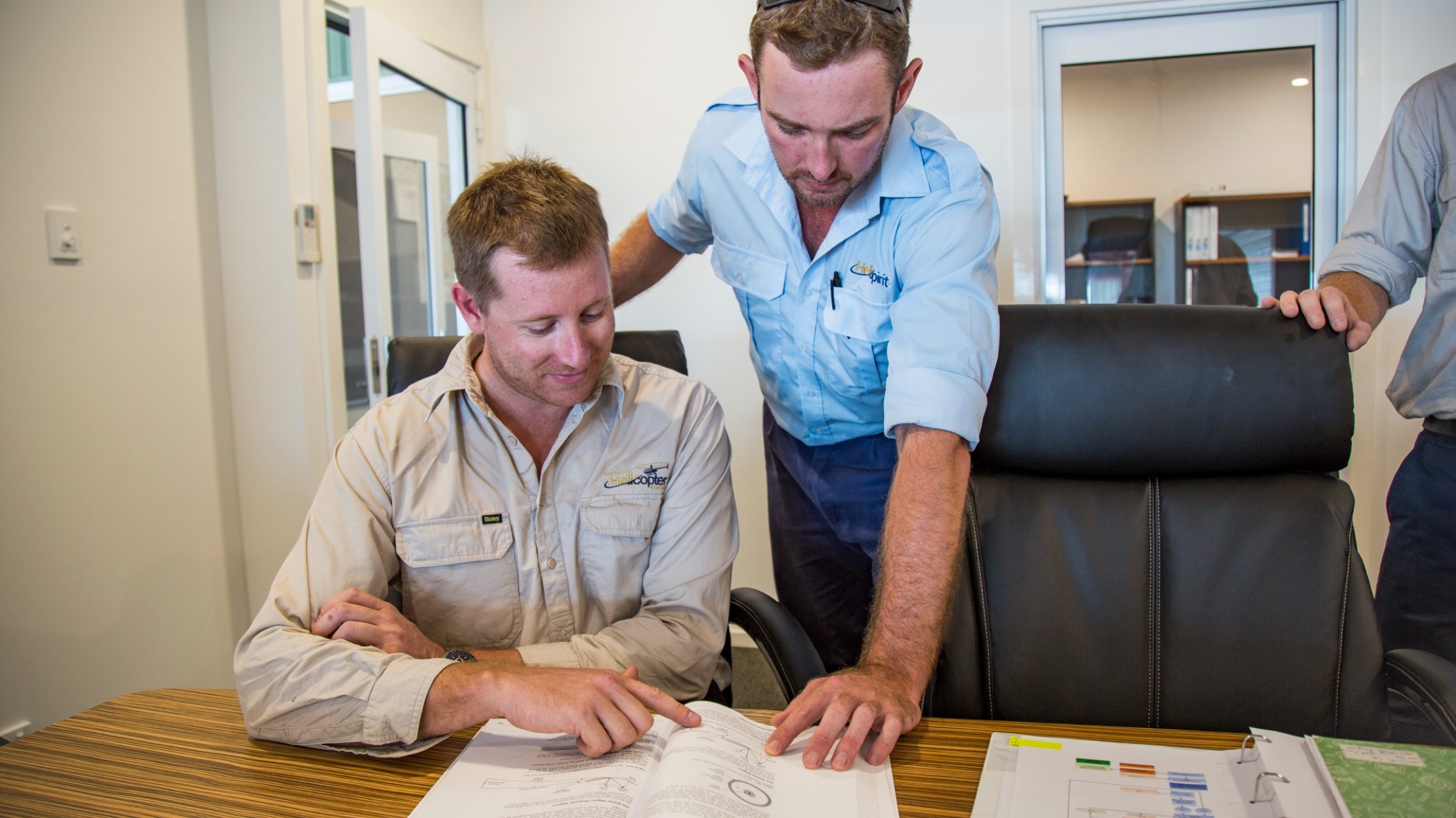 Two men in a meeting room examining a document together.