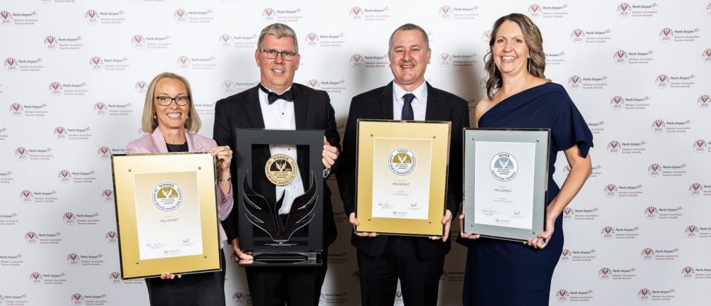 Four people holding framed awards in front of a logoed backdrop.