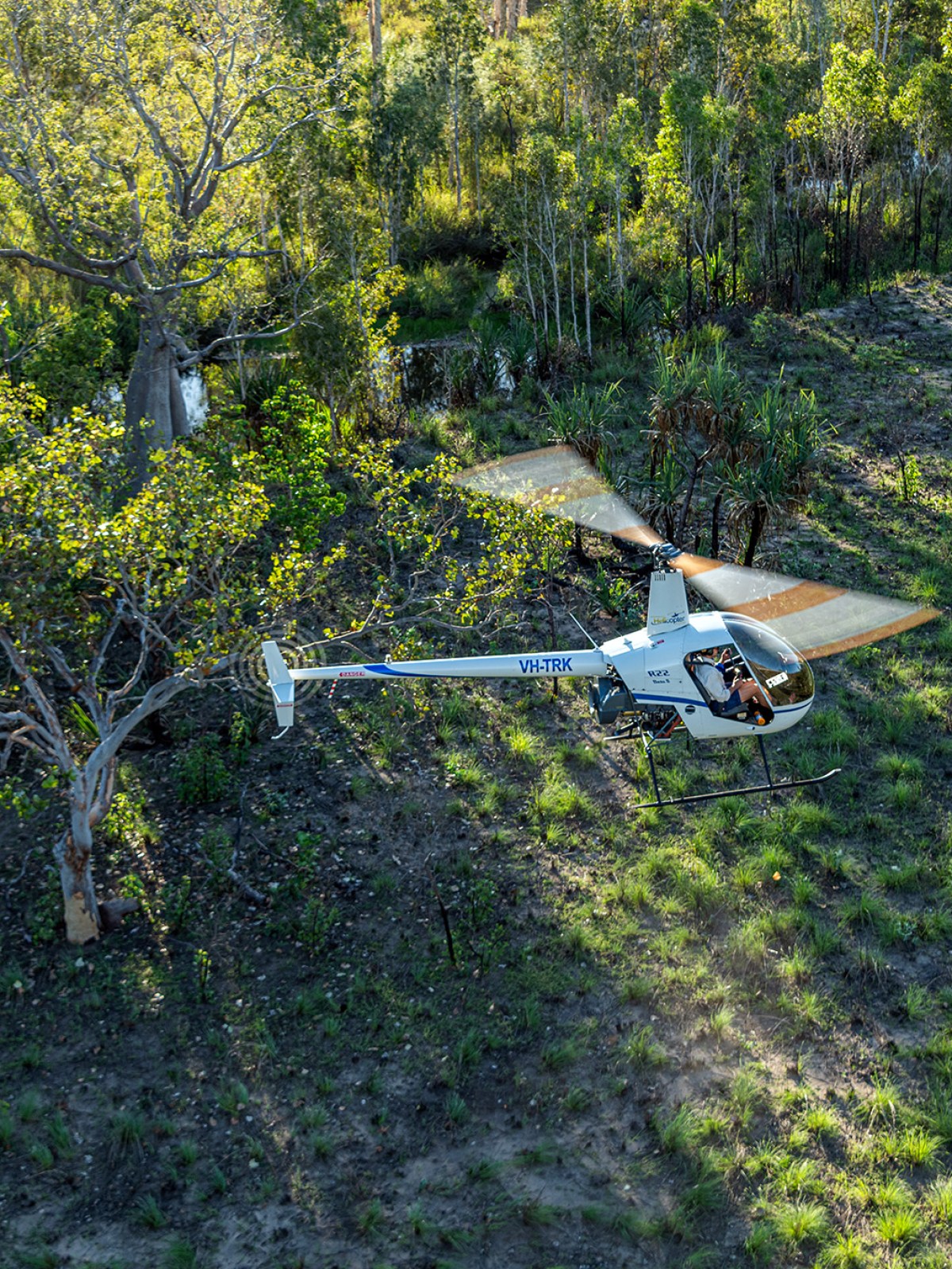 Aerial view of a helicopter flying over a green, forested area.