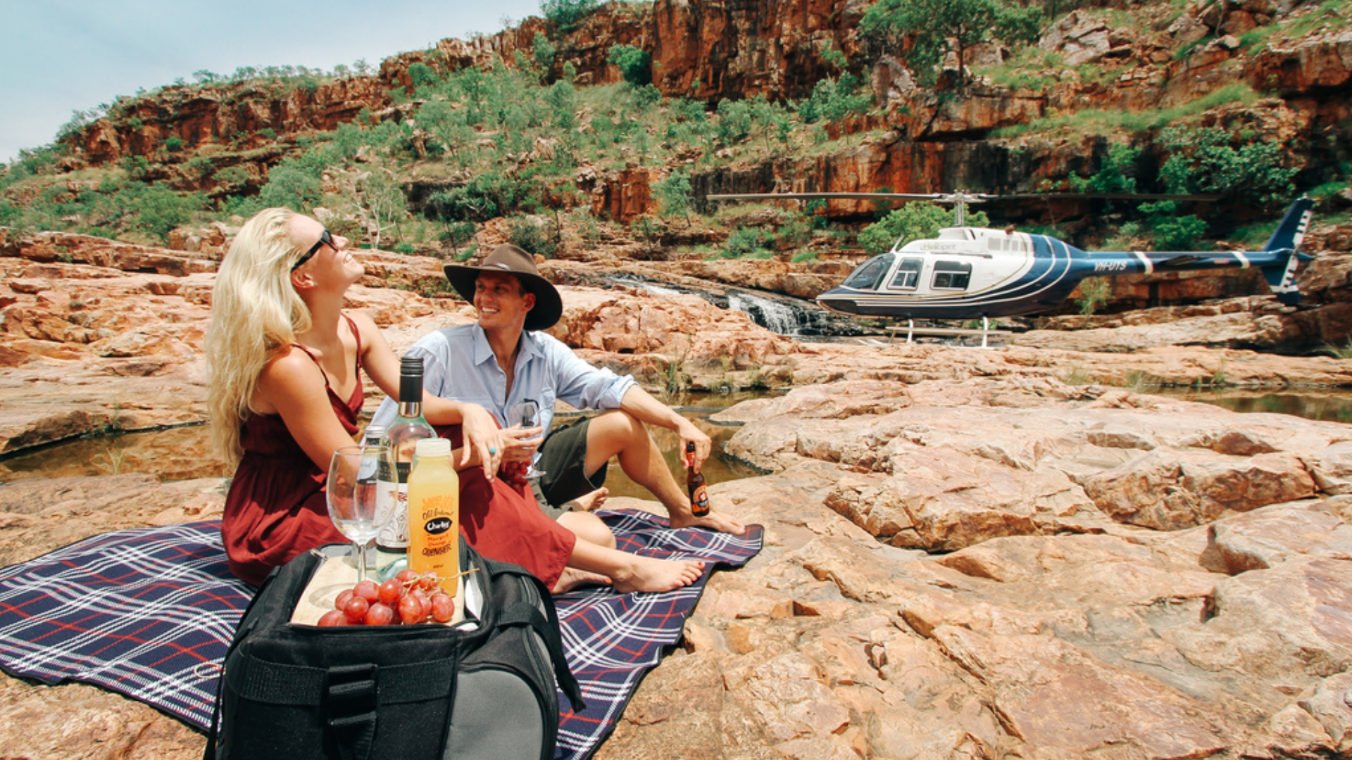 Couple having a picnic on rocky terrain with a helicopter in the background.